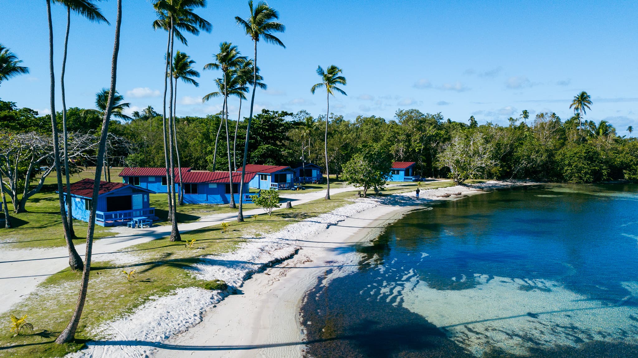 Cabañas azules con techo rojo entre palmeras frente al mar en Villa La Mela, Cabo Rojo, Puerto Rico